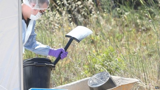 Forensic officers have been seen filling buckets with earth