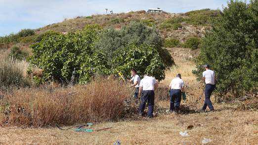 Police officers clear an area of wasteland during the search